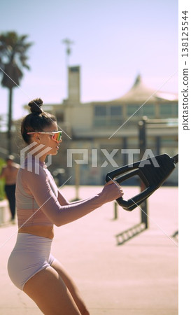 Female athlete exercising on handcycle machine near coastal scenery Female athlete exercising on handcycle machine near coastal scenery 138125544