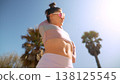 Fitness enthusiast engaging in dynamic warmup near palm trees 138125545