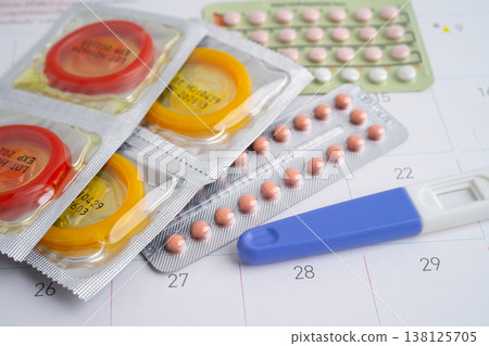 Pregnancy test and condom for female on calendar, ovulation day. Pregnancy test and condom for female on calendar, ovulation day. 138125705