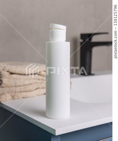 White blank flip top cosmetic bottle near bath towel in beige bathroom, cosmetic mockup White blank flip top cosmetic bottle near bath towel in beige bathroom, cosmetic mockup 138125796
