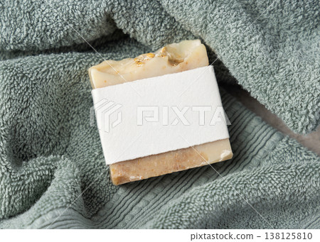 Beige solid soap bar mockup with blank paper label on sage green bath towel, unbranded packaging Beige solid soap bar mockup with blank paper label on sage green bath towel, unbranded packaging 138125810