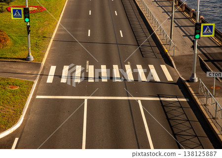 Empty zebra crosswalk on city asphalt road with green traffic light. Pedestrian crossing with lane markings. Urban transportation infrastructure and safe street travel concept. Empty zebra crosswalk on city asphalt road with green traffic light. Pedestrian crossing with lane markings. Urban transportation infrastructure and safe street travel concept. 138125887