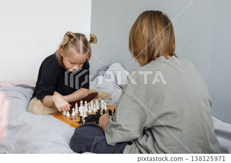 Thinking little girl and young boy have a nice game. Sibling playing chess  138125971