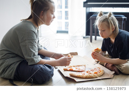 Indoor portrait of kids sibling eating pizza at home. Little girl and boy children portrait Indoor portrait of kids sibling eating pizza at home. Little girl and boy children portrait 138125973