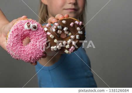 Two tasty Donuts in hands. Pink and chocolate doughnuts, sweet dessert food Two tasty Donuts in hands. Pink and chocolate doughnuts, sweet dessert food 138126084