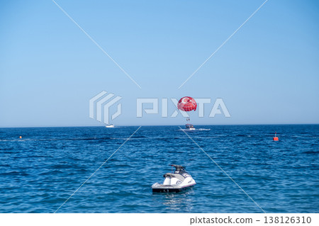 Parasailing Adventure Over Clear Blue Waters With Jet Ski in Foreground 138126310