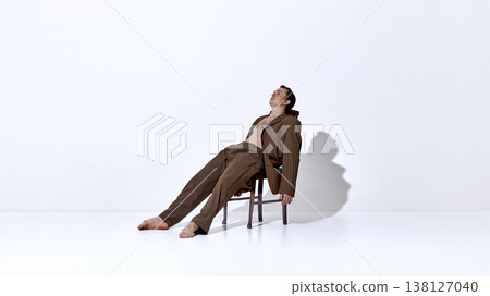 Male dancer leaning back on chair in relaxed expressive pose inside studio. 138127040