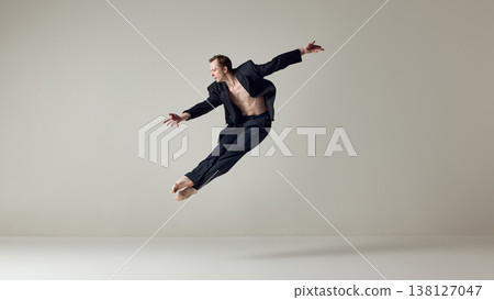 Male dancer captured in horizontal flight pose with extended body line in studio. Male dancer captured in horizontal flight pose with extended body line in studio. 138127047