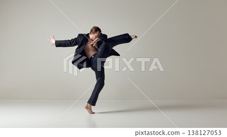 Male dancer executing powerful high kick with dynamic upper body motion in studio. 138127053