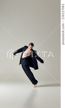 Male dancer balancing barefoot in loose suit during expressive movement Male dancer balancing barefoot in loose suit during expressive movement 138127061