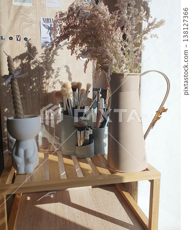 Organizer with makeup brushes and decorative vase with dried flowers on a wooden shelf Organizer with makeup brushes and decorative vase with dried flowers on a wooden shelf 138127366