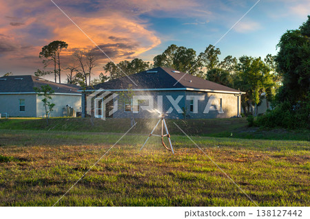 Lawn grass watering with automated sprinkler. Keeping green backyard during dry season 138127442