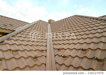 House roof surface covered with brown metal tile sheets. House roof surface covered with brown metal tile sheets. 138127478