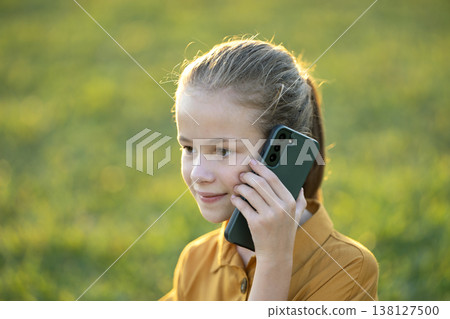 Happy pretty child girl talking on her cellphone in summer park Happy pretty child girl talking on her cellphone in summer park 138127500