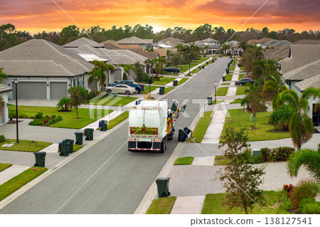 Garbage truck loading trash bin from the curb of American neighborhood Garbage truck loading trash bin from the curb of American neighborhood 138127541