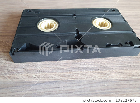 Black retro VHS video cassette lying on a wooden surface 138127673