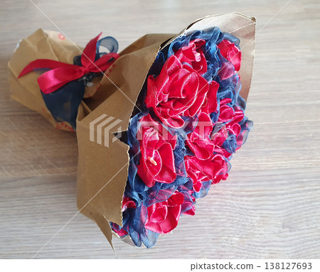 Artificial bouquet of red and blue fabric roses wrapped in brown craft paper with a red ribbon Artificial bouquet of red and blue fabric roses wrapped in brown craft paper with a red ribbon 138127693