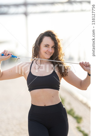 Woman smiling holding jump rope exercising outdoors Woman smiling holding jump rope exercising outdoors 138127756