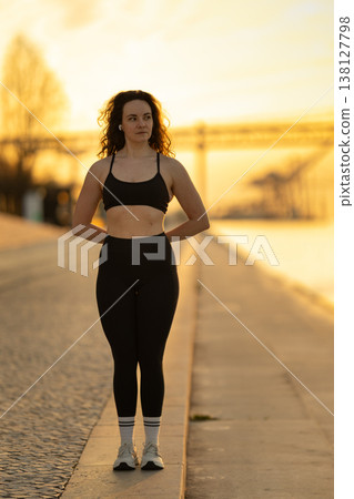 Woman standing by river at golden hour preparing for workout Woman standing by river at golden hour preparing for workout 138127798