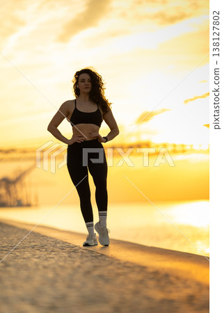 Woman standing by water at golden sunset 138127802