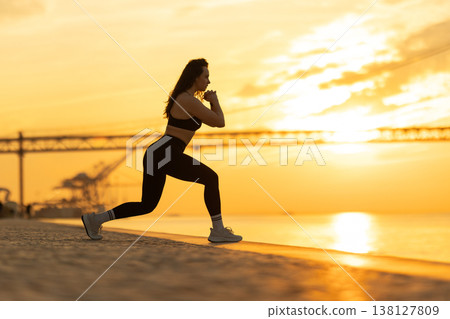 Woman exercising lunge on waterfront at sunset 138127809