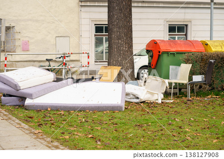 Illegal dumping of old furniture and waste near residential garbage bins, urban pollution problem, environmental issue and improper disposal concept 138127908