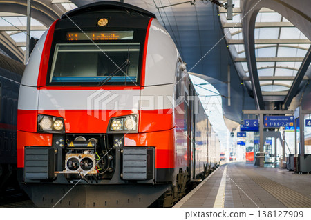Modern passenger train standing at station platform, urban transport infrastructure with railway tracks, architecture and travel concept Modern passenger train standing at station platform, urban transport infrastructure with railway tracks, architecture and travel concept 138127909