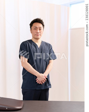 A male chiropractor standing in the treatment room of a chiropractic clinic. A male chiropractor standing in the treatment room of a chiropractic clinic. 138128001