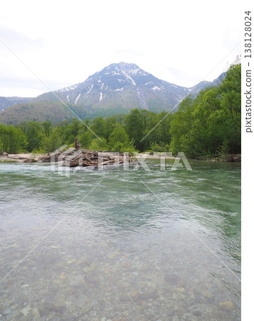 The Azusa River in Kamikochi, with its fresh greenery and snow-capped mountains, creates a beautiful mountain landscape. 138128024