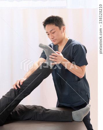 A chiropractor performing leg stretching treatments at a chiropractic clinic. 138128210