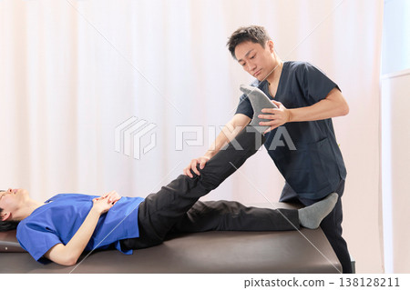一位脊椎按摩師正在脊椎按摩診所進行腿部拉伸治療。 一位脊椎按摩師正在脊椎按摩診所進行腿部拉伸治療。 138128211