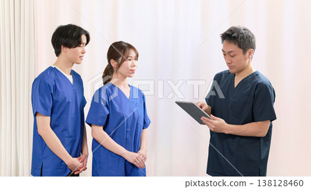 Medical staff meeting while looking at electronic medical records Medical staff meeting while looking at electronic medical records 138128460