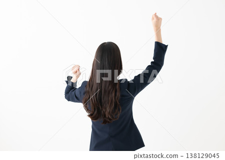一位女性背對著鏡頭,舉起雙臂做出慶祝的姿勢。 一位女性背對著鏡頭,舉起雙臂做出慶祝的姿勢。 138129045
