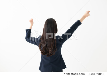 一位女性背對著鏡頭,舉起雙臂做出慶祝的姿勢。 一位女性背對著鏡頭,舉起雙臂做出慶祝的姿勢。 138129046