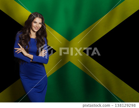 Friendly young woman in blue dress smiling against flag of Jamaica background Friendly young woman in blue dress smiling against flag of Jamaica background 138129298