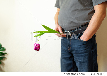 Erectile dysfunction concept. Man holding a flower bending downwards. Erectile dysfunction concept. Man holding a flower bending downwards. 138129403