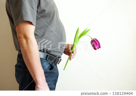 Erectile dysfunction concept. Man holding a flower bending downwards. Erectile dysfunction concept. Man holding a flower bending downwards. 138129404