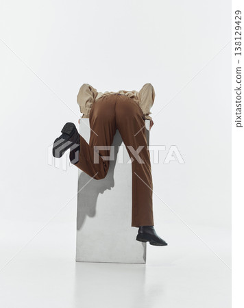 Person leaning forward over white pedestal in studio isolated on white background. Person leaning forward over white pedestal in studio isolated on white background. 138129429