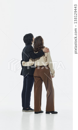 Man and woman standing together from behind looking forward in studio. 138129443