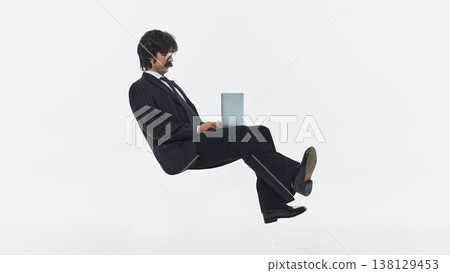 Businessman floating while using laptop isolated on white background studio shot. Businessman floating while using laptop isolated on white background studio shot. 138129453