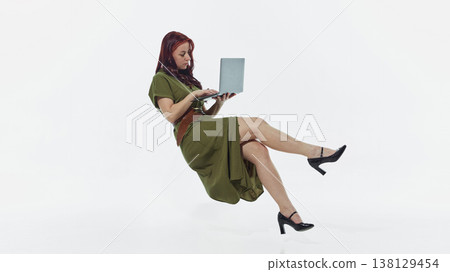 Woman floating while using laptop isolated on white background minimal studio shot. Woman floating while using laptop isolated on white background minimal studio shot. 138129454