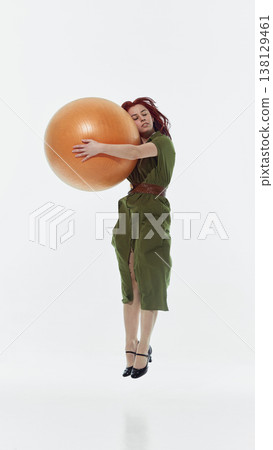 Woman holding large exercise ball standing in studio isolated on white Woman holding large exercise ball standing in studio isolated on white 138129461