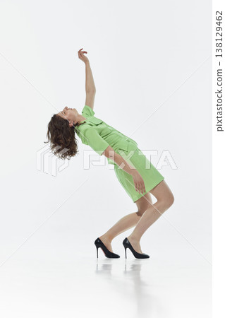 Woman in modern outfit leaning backward in stylized motion in studio. Woman in modern outfit leaning backward in stylized motion in studio. 138129462