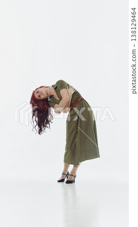 Woman in green dress bending sideways expressive pose in studio isolated on white 138129464