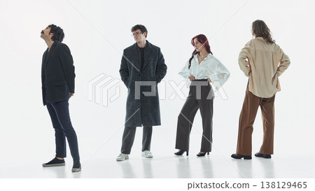 Group of stylish people standing apart and looking in different directions in studio. Group of stylish people standing apart and looking in different directions in studio. 138129465