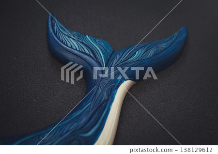 Close-up of a carved wooden whale tail featuring intricate blue carved patterns and textures on a dark background. Close-up of a carved wooden whale tail featuring intricate blue carved patterns and textures on a dark background. 138129612