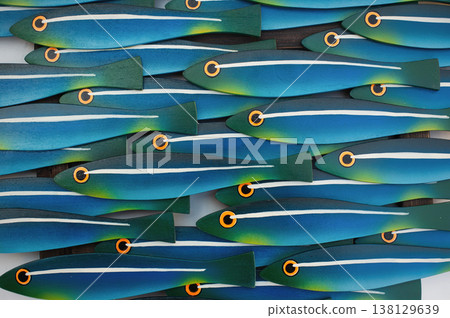 Macro shot of a school of stylized wooden fish with vibrant turquoise, blue, and yellow gradients on a white background. Macro shot of a school of stylized wooden fish with vibrant turquoise, blue, and yellow gradients on a white background. 138129639
