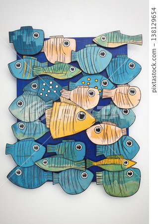 Frontal view of a handcrafted wooden wall art panel featuring a school of stylized, colorful fish on a dark blue base. Frontal view of a handcrafted wooden wall art panel featuring a school of stylized, colorful fish on a dark blue base. 138129654