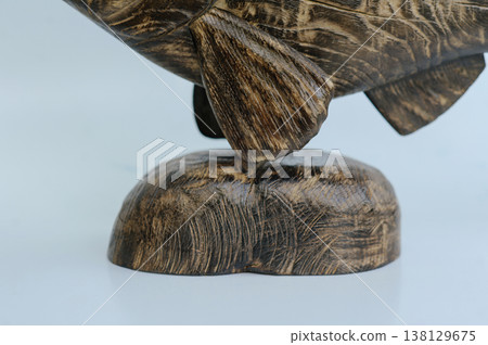 Macro shot of a hand-carved wooden fish sculpture base, highlighting the stone-like texture of the pedestal and the detailed craftsmanship of the lower fins Macro shot of a hand-carved wooden fish sculpture base, highlighting the stone-like texture of the pedestal and the detailed craftsmanship of the lower fins 138129675