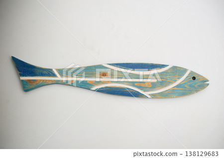 High-angle frontal view of an elongated decorative wooden fish with a distressed turquoise body, blue tail, and white stripe inlays on a light gray background. 138129683
